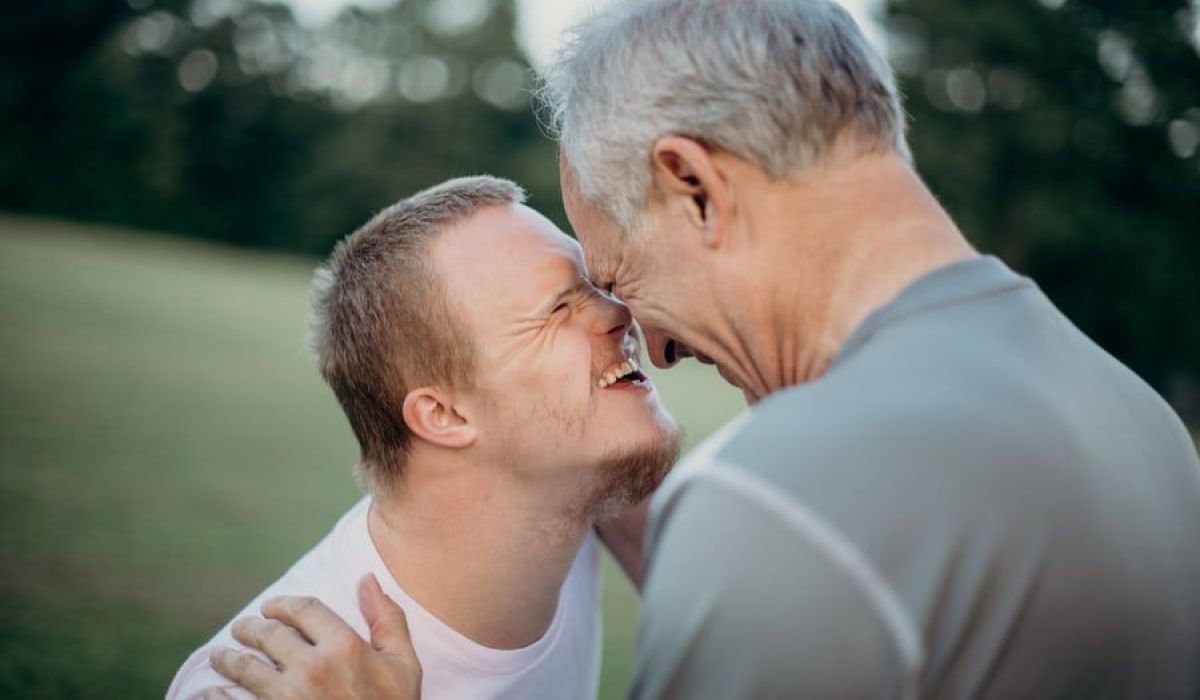 Kvinnlig handledare sitter bredvid en ung man med Downs syndrom.