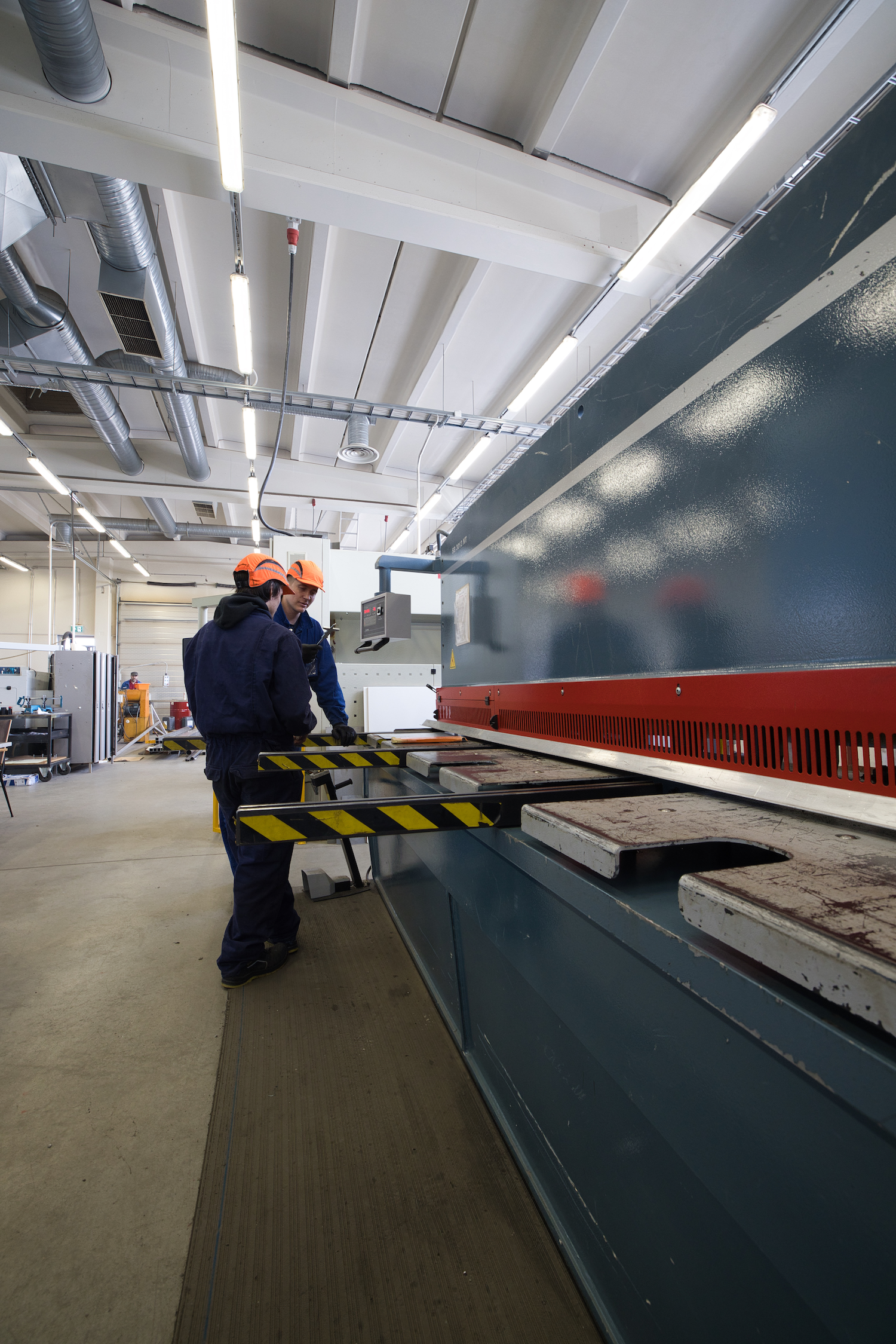 Två metallarbetare står framför en stor metallbearbetningsmaskin